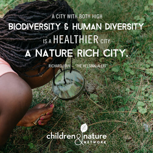 Girl looking with magnifying glass on grass. Photo caption: A city with both high biodiversity and human diversity is a healthier city - a nature rich city. Quote by RIchard Louv - "The Helsinki Alert"