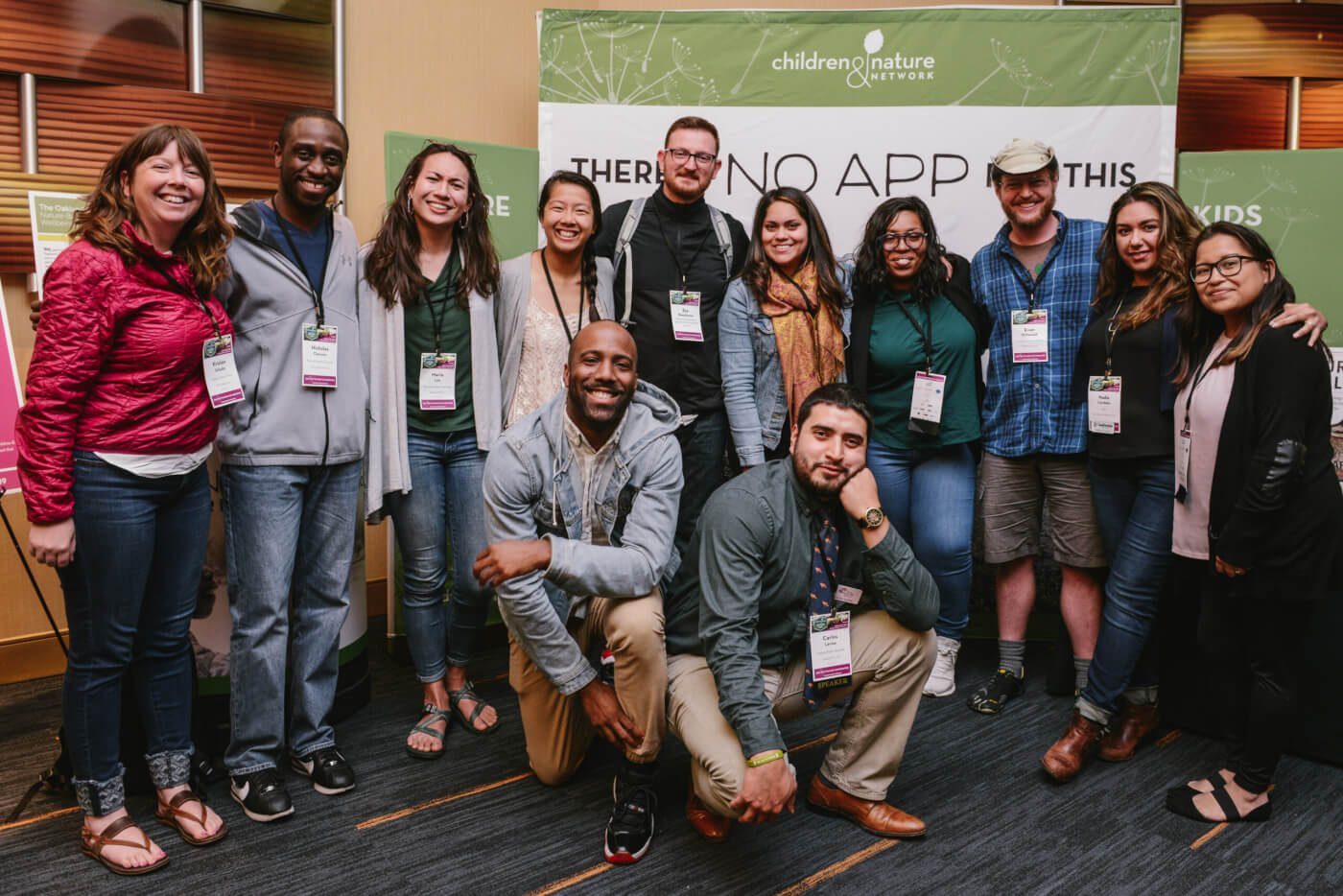 CJ Goulding poses in front of a banner with 11 other members of the Natural Leaders Network at a conference.