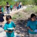 Children on a nature walk, carrying clipboards and pencils on a sunny trail.