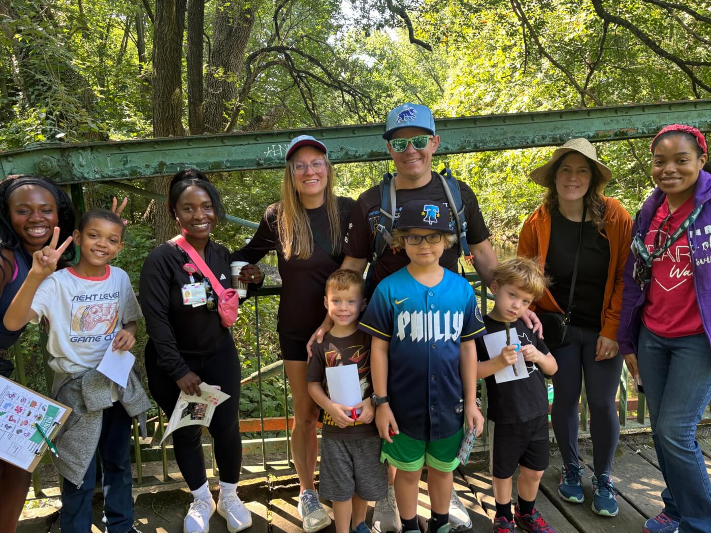 Group of adults and children posing on a wooded bridge during an outdoor activity.