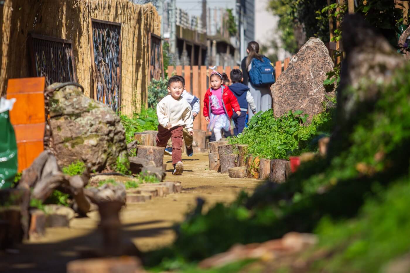 Young children run into a nature-filled play space.