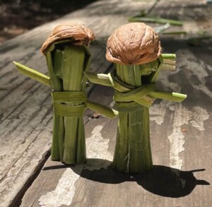 Small handmade tule dolls wearing walnut shell hats, displayed on a table.