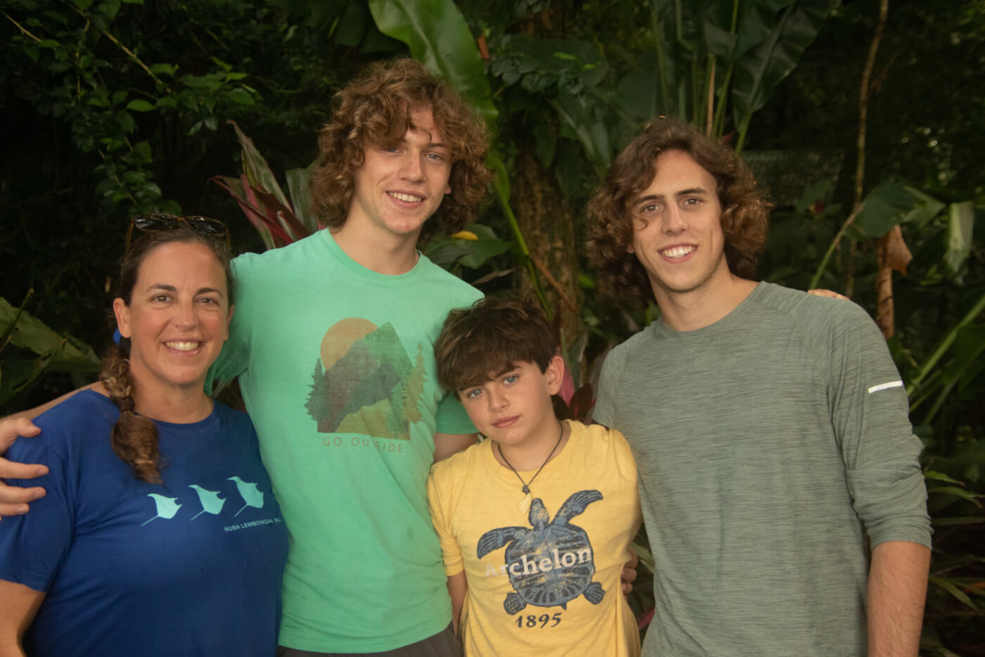 family smiling at camera with trees in the background
