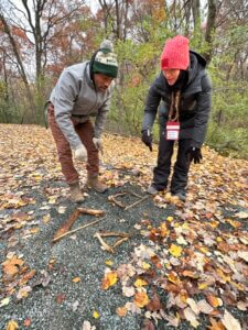 Two teachers develop basic geometry lessons by arranging sticks on the ground to explore shapes and spatial relations.