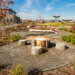A Nature Exploration Area features a sitting area built from three tree stumps circling a larger tree stump. The area is ringed with a border of mulch and flowers.