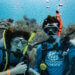 two people under the water with scuba gear on in front of a reef