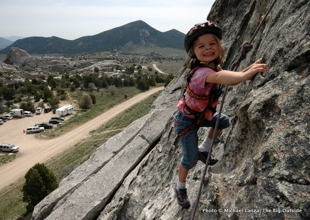 Kid rock climbing on side of cliff.