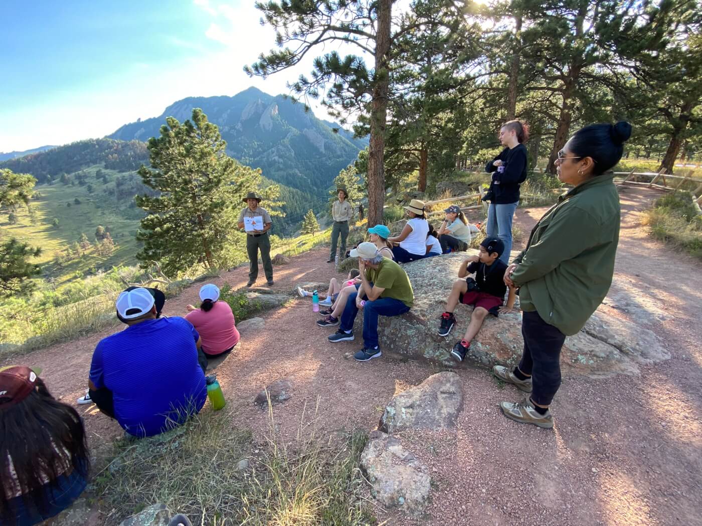 Leidy Pineda Flores leading a bilingual nature program in the forest with a diverse, attentive audience.