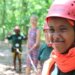 Girl smiling wearing tree climbing gear.