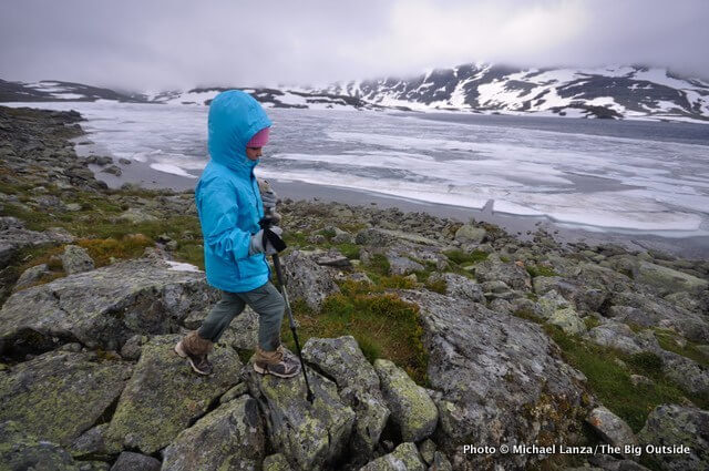 Child walking along lake near rocks.