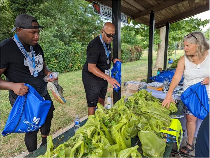 People collecting bags of fresh produce at an outdoor community distribution table.