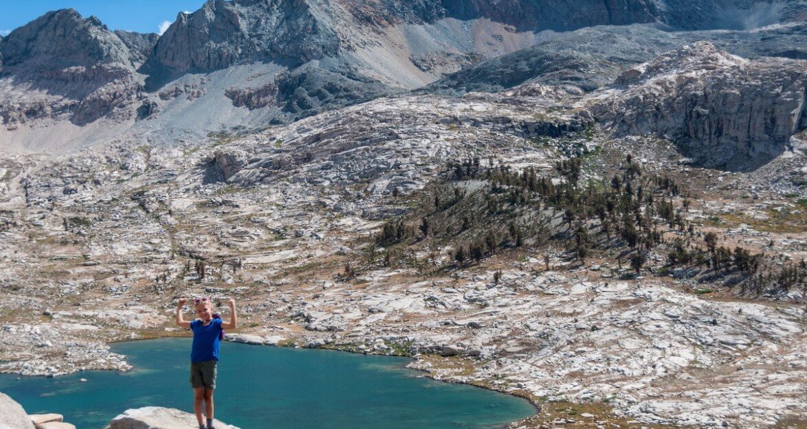 Triumphant child posing in front of view from top of cliff.