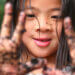 Young girl smiling and holding out muddy hands.