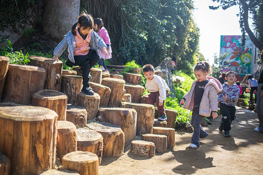 Kids playing on wooden stumps in a playground in San Francisco.