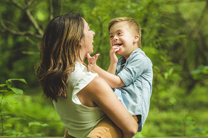 Woman holding child outside in a forest.