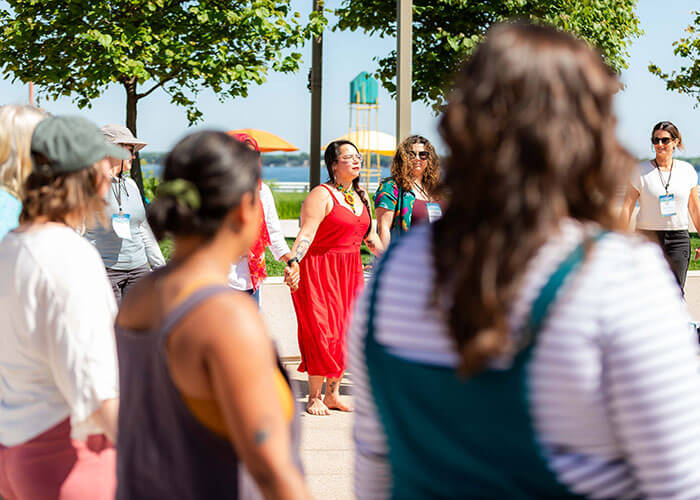 Conference attendees holding hands outside.