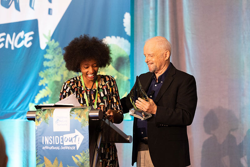 Richard Louv presents the inaugural Richard Louv Prize to Atiya Wells at the 2022 Inside-Out International Conference.