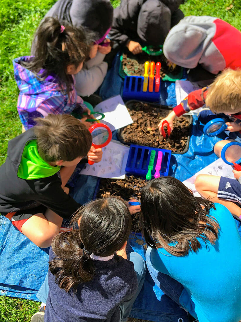 Kids using tools to inspect dirt and other items.