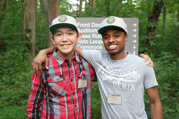Two boys together by a trail sign.