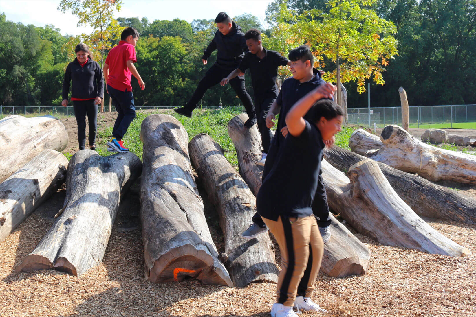 Children playing by wooden log play area.
