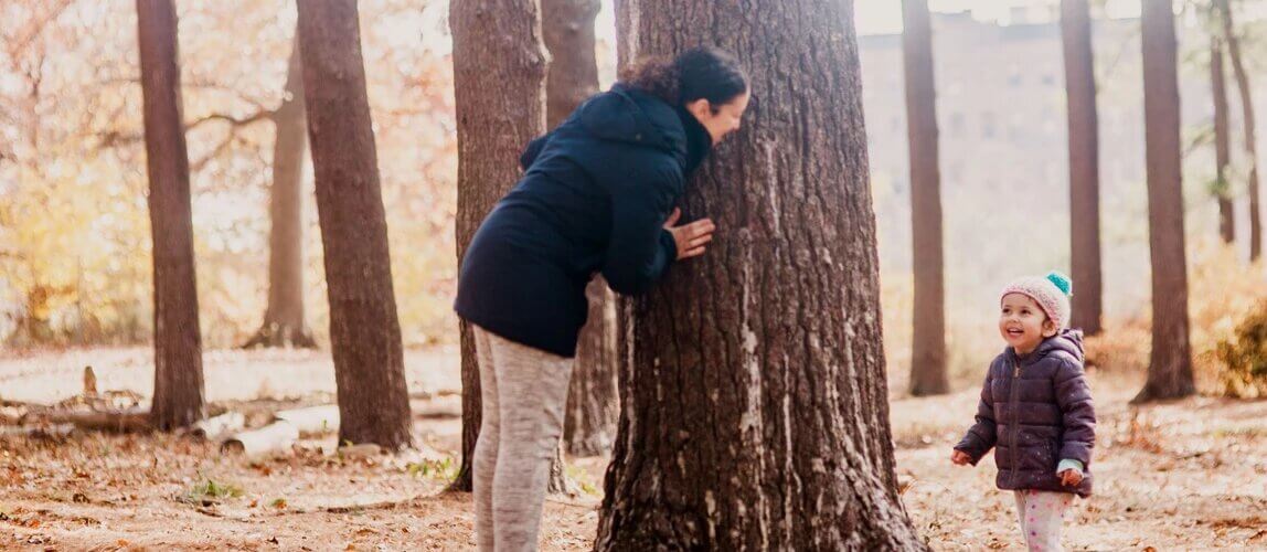 parent playing hide-and-seek with child in forest