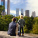 man and his son on top of a rock in central park, looking down at the park