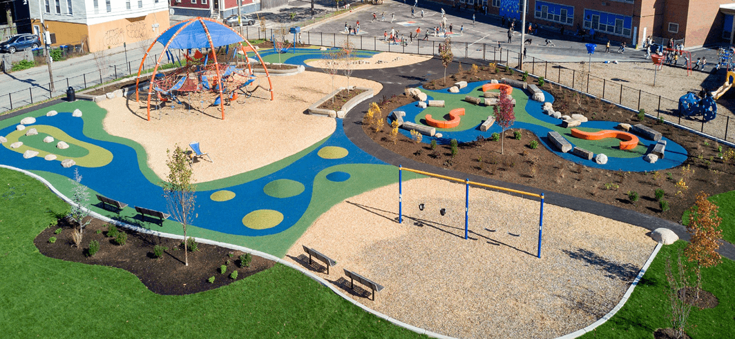 erial view of Harriet and Sayles Park and the Mary E. Fogarty Green Schoolyard Complex, showing colorful play areas, swings, climbing structures, and landscaped paths. Photo credit: Providence Parks Department.