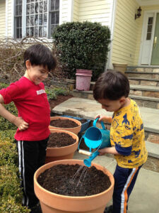 two kids watering a pot