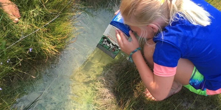 kid looking through a scope made out of a milk carton at water