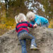 Two children play in the mud.
