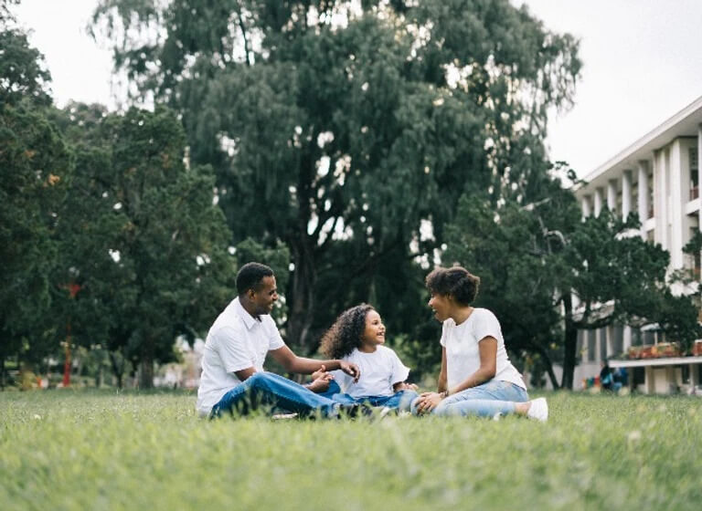 family of three sitting in a park