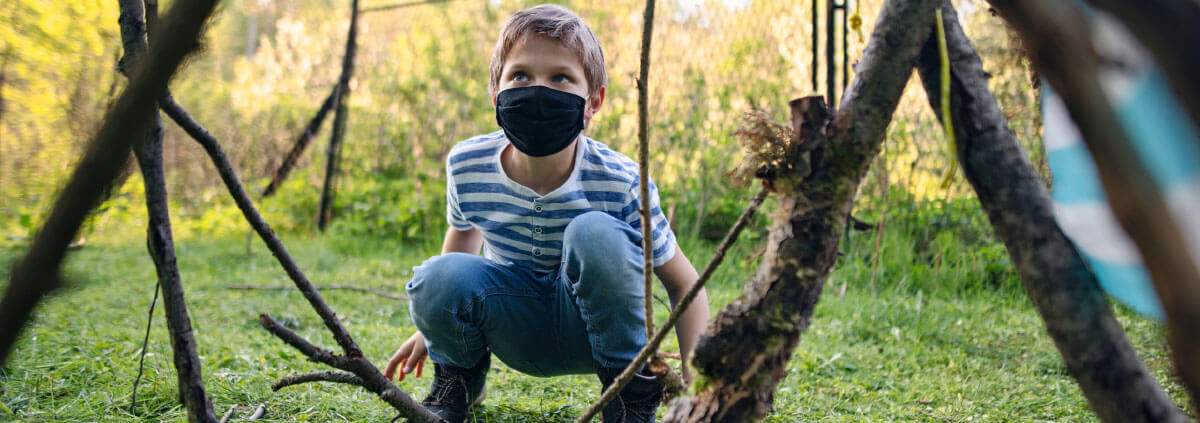 Young boy with mask on in forest.
