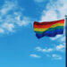 flagpole with pride flag and blue sky
