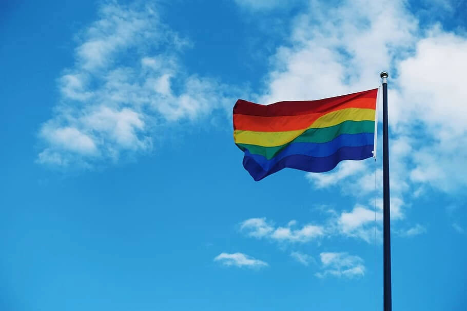 flagpole with pride flag and blue sky