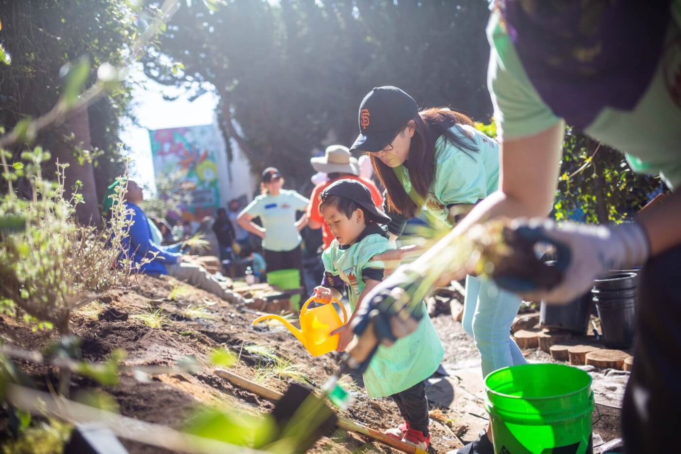 Young children and adults work together to install a nature-filled play space at an early child care center.