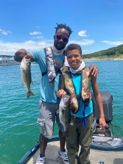 father and son hold up fishes they caught