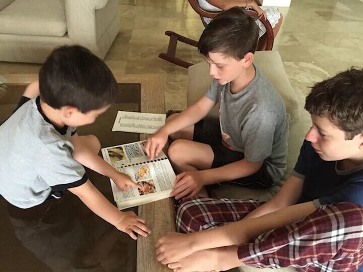three kids looking at a book