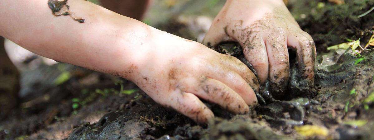 Child's hands playing in dirt.