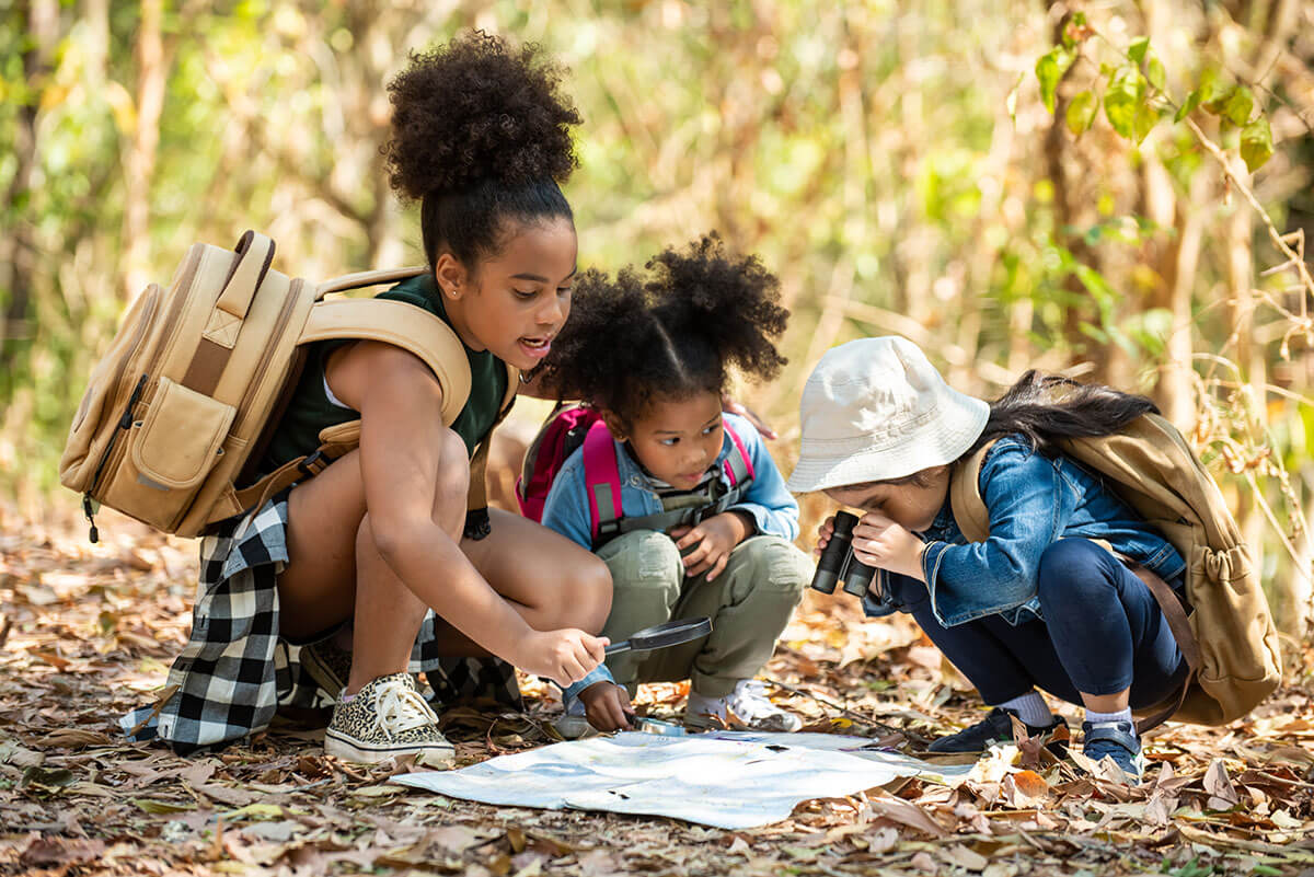 Three Kids Looking at Map Outdoors