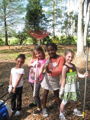 Girls standing with shovels.