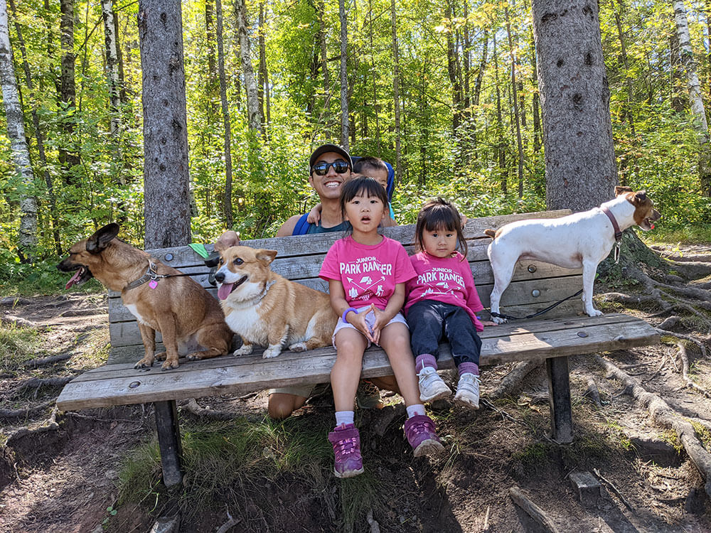 Kong, their kids, and their dogs sitting on a bench.