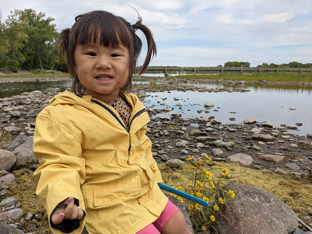 Maria sitting on a rocky beach.